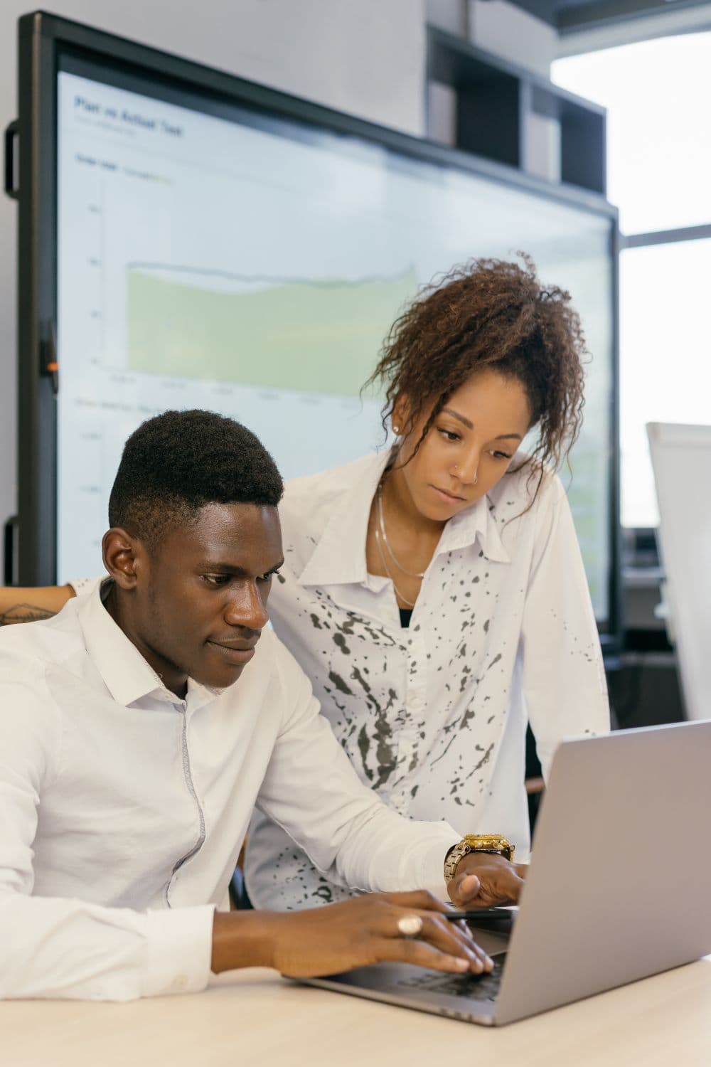 Two colleagues reviewing work on a laptop
